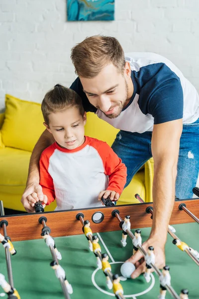 Padre e hijo jugando futbolín juntos en casa - foto de stock