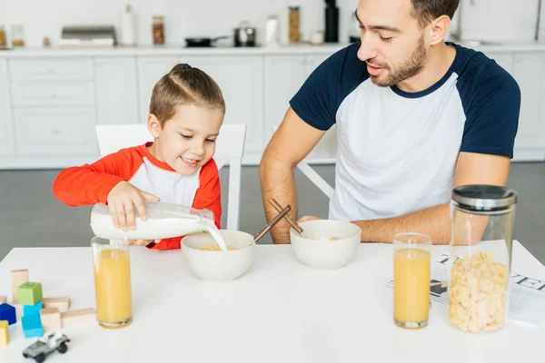 Glücklicher Vater und kleiner Sohn beim gemeinsamen Frühstück in der heimischen Küche — Stockfoto