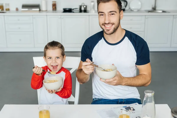 Счастливый отец и маленький сын завтракают вместе на кухне дома — стоковое фото
