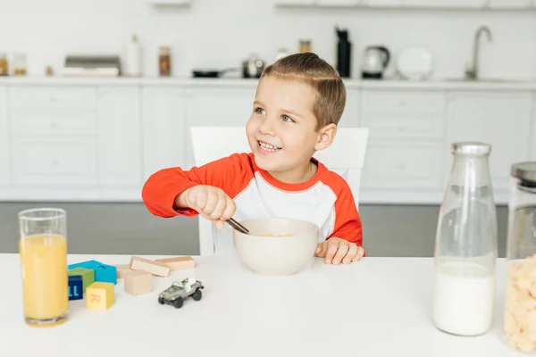 Portrait de petit garçon souriant prenant le petit déjeuner dans la cuisine à la maison — Photo de stock