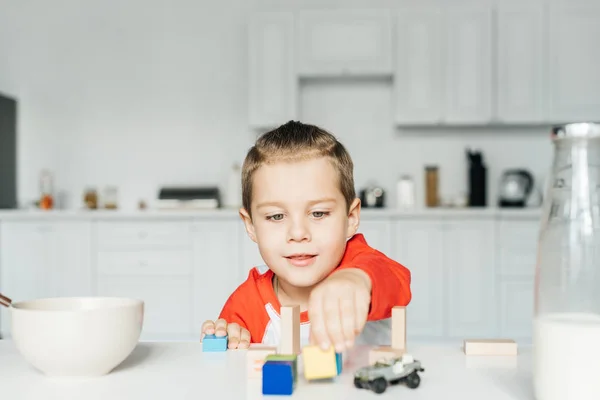 Menino brincando com blocos de madeira na cozinha em casa — Fotografia de Stock