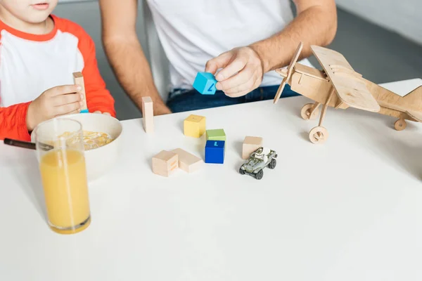 Partial view of father and son playing with wooden blocks after breakfast in kitchen — Stock Photo