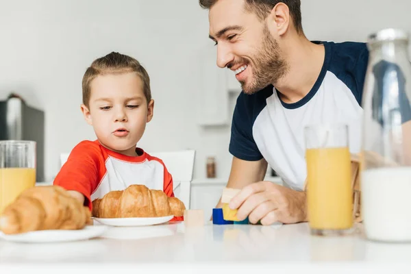 Nahaufnahme Porträt eines lächelnden jungen Vaters und seines Sohnes beim gemeinsamen Frühstück zu Hause — Stockfoto