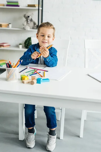Счастливый ребенок рисует цветными карандашами дома — стоковое фото