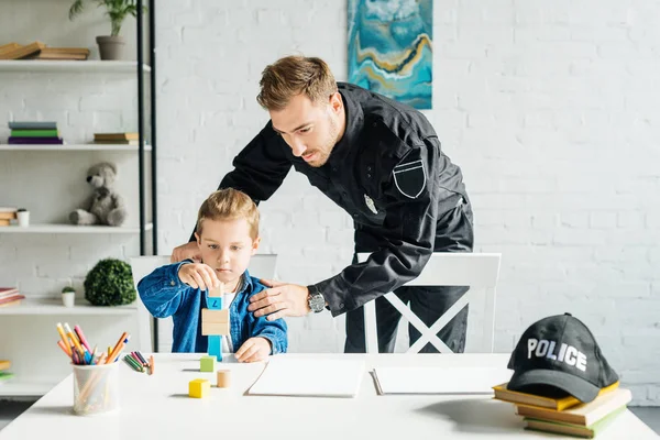 Jeune père en uniforme de police et fils jouant ensemble à la maison — Photo de stock