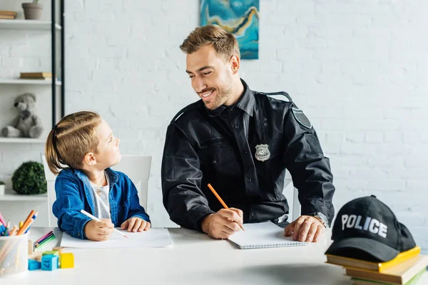 Glücklicher junger Vater in Polizeiuniform und Sohn ziehen zu Hause an einem Strang — Stockfoto