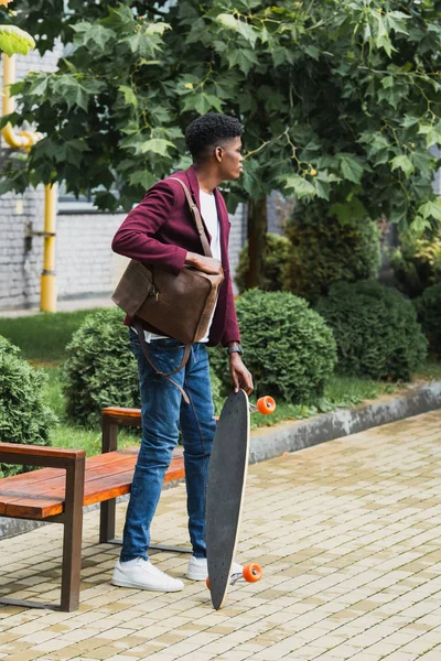 Junge Studentin mit Rucksack und Skateboard steht auf Straße — Stockfoto