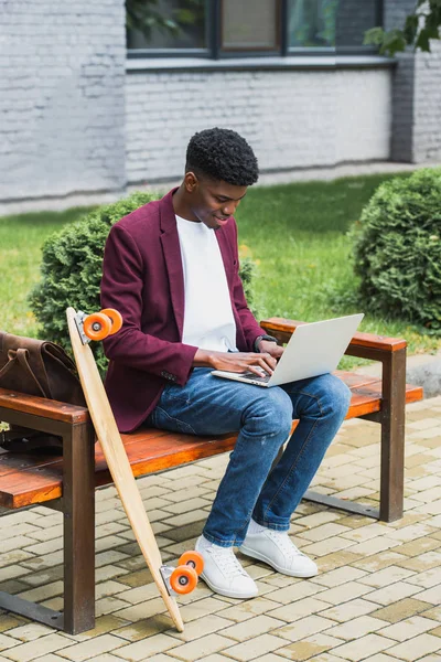 Feliz afroamericano freelancer utilizando portátil en la calle - foto de stock