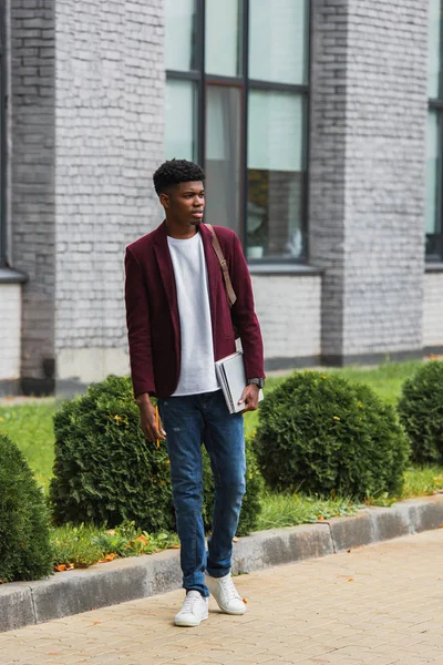 Schöner junger Student mit Rucksack und Notizbüchern, der auf der Straße steht — Stockfoto