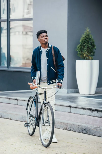 Guapo afroamericano freelancer con documentos y bicicleta - foto de stock