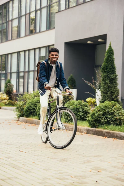 Joven afroamericano montando bicicleta en la ciudad - foto de stock