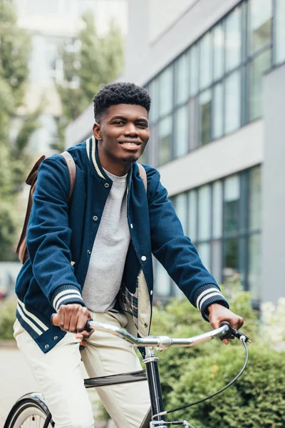 Handsome cheerful african american man riding bicycle in city — Stock Photo