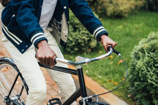 Abgeschnittene Ansicht eines afrikanisch-amerikanischen Mannes, der im Park Fahrrad fährt — Stockfoto