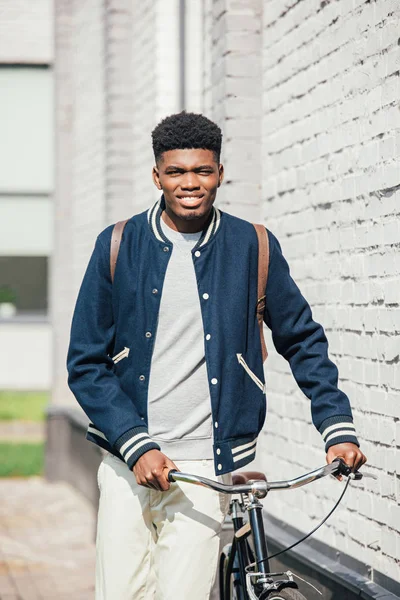 Афроамериканський стильний чоловік з велосипедом, що стоїть біля білої цегляної стіни — стокове фото