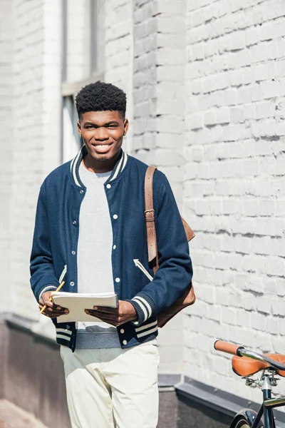 Bonito elegante estudante afro-americano segurando livro didático — Fotografia de Stock