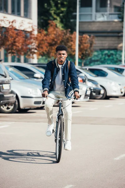 Guapo afroamericano hombre montar bicicleta de moda en la ciudad - foto de stock