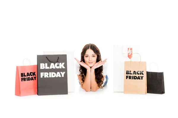 Happy stylish shopaholic lying at shopping bags with black friday symbols isolated on white — Stock Photo