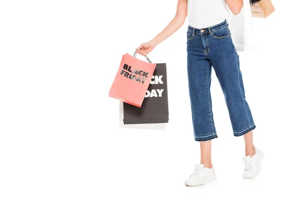 Vista parcial de chica de moda sosteniendo bolsas de compras con letreros de venta de viernes negro aislados en blanco - foto de stock