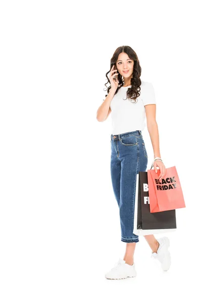 Client parlant sur smartphone et tenant des sacs à provisions avec panneau noir vendredi isolé sur blanc — Photo de stock