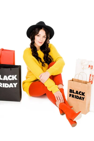 Elegante shopaholic sentado en bolsas de compras en la venta de viernes negro, aislado en blanco - foto de stock