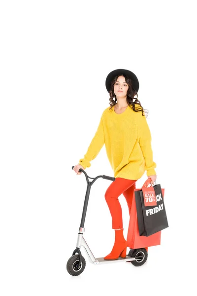 Красивая молодая женщина на скутере с пакетами для покупок черной пятницы изолированы на белом — стоковое фото