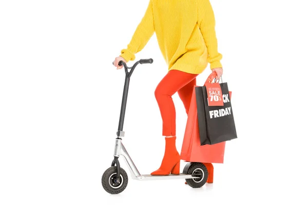 Vista ritagliata di ragazza equitazione scooter con shopping bags per venerdì nero isolato su bianco — Foto stock