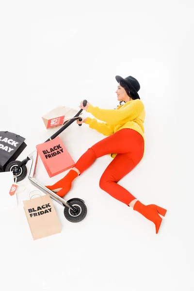 Top view of female customer riding scooter with shopping bags for black friday isolated on white — Stock Photo