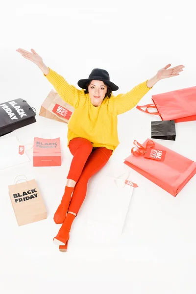 Aufgeregte Frau, die am Black Friday Sale an Einkaufstaschen sitzt, isoliert auf weiß — Stockfoto