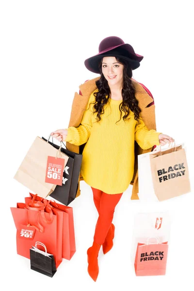 Menina elegante segurando cartão de crédito e sacos de compras para sexta-feira preta isolado no branco — Fotografia de Stock