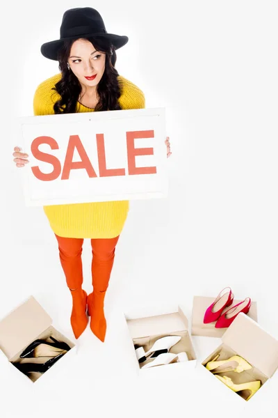 Молода стильна жінка тримає знак продажу ізольована на білому з високими підборами — стокове фото