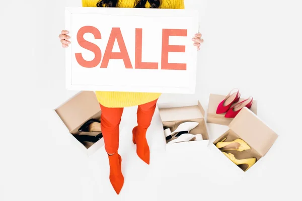 Обрізаний вид дівчини, що тримає знак продажу ізольовано на білому з взуттям — стокове фото