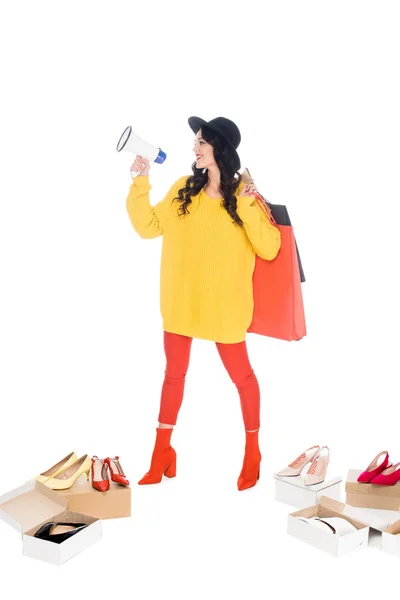 Belle jeune femme tenant mégaphone et sacs à provisions isolés sur blanc avec des chaussures — Photo de stock