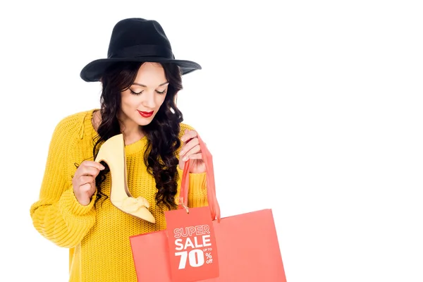 Bella donna elegante in possesso di calzature e shopping bag e tag vendita isolato su bianco — Foto stock