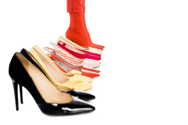 Cropped shot of female legs and arranged shoes isolated on white — Stock Photo