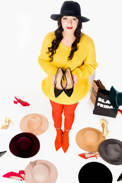 High angle view of young woman with shoes, hats and shopping bags with black friday lettering inscription around isolated on white — Stock Photo