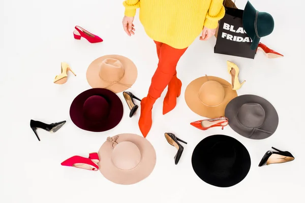 Vista parcial de mujer, zapatos femeninos, sombreros y bolsas de compras con inscripción de viernes negro aislado en blanco - foto de stock