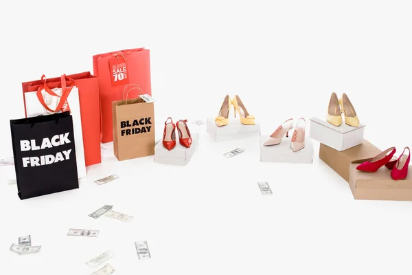 Close up view of dollar banknotes, female footwear and shopping bags with black friday lettering on white background — Stock Photo