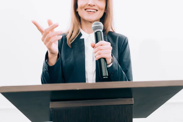 Cropped image of smiling speaker gesturing and talking at podium tribune during seminar in conference hall — Stock Photo