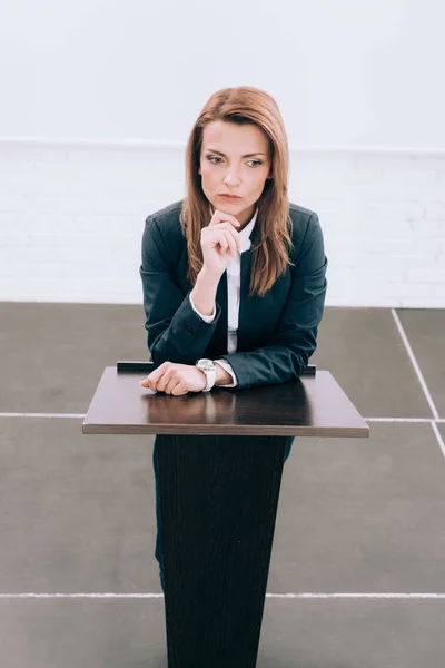 High angle view of pensive attractive lecturer standing at podium tribune during seminar in conference hall — Stock Photo