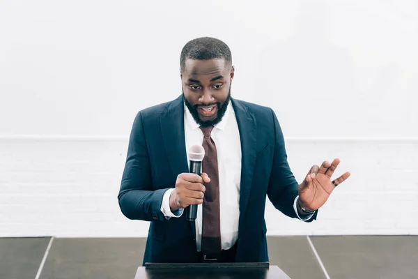 Высокий угол обзора улыбающегося африканского говорящего американца в микрофон во время семинара в конференц-зале — стоковое фото