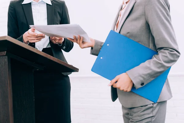 Cropped image of assistant giving documents to speaker during seminar in conference hall — Stock Photo