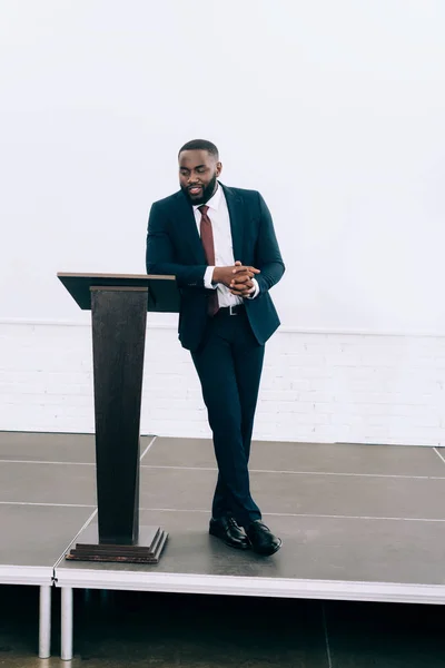 Schöner afrikanisch-amerikanischer Geschäftsmann lehnt auf Podiumstribüne und spricht während eines Seminars im Konferenzsaal — Stockfoto