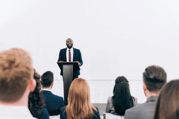 Smiling african american lecturer talking to audience during seminar in conference hall — Stock Photo