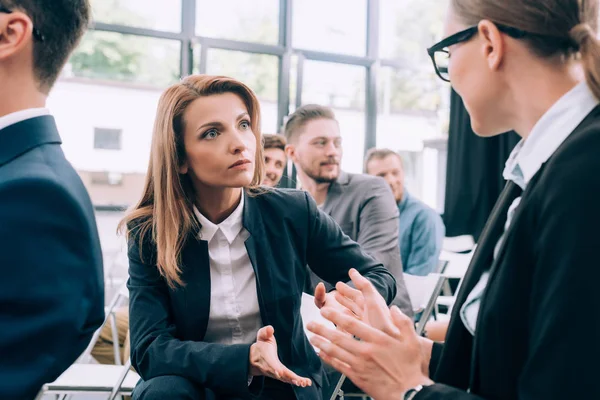 Attractive businesswomen sitting on chairs and talking in conference hall — Stock Photo