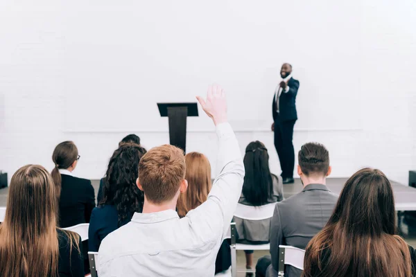 Visão traseira do ouvinte levantando a mão durante o seminário na sala de conferências — Fotografia de Stock