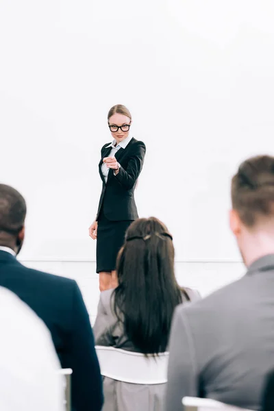 Attrayant conférencier pointant sur le public multiculturel pendant le séminaire dans la salle de conférence — Photo de stock