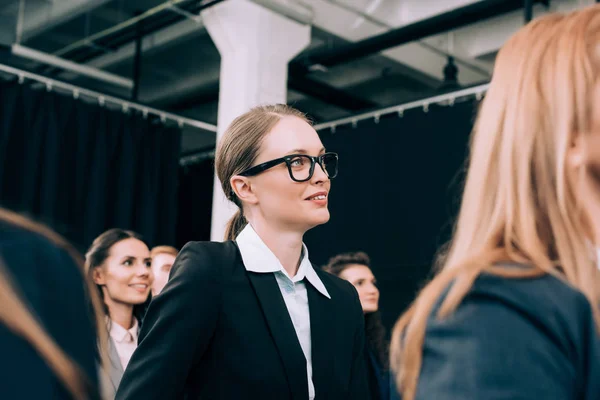 Selective focus of businesswoman in eyeglasses listening to speaker during seminar in conference hall — Stock Photo