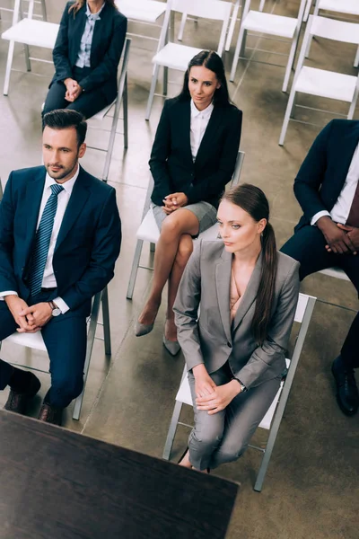 Visión de alto ángulo de los empresarios multirraciales que escuchan al profesor durante el seminario de negocios en la sala de conferencias - foto de stock