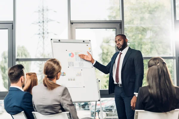 African american businessman pointing at white board during business seminar in conference hall — Stock Photo