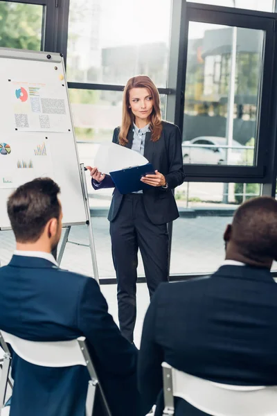 Female business lecturer presenting material during seminar with multicultural colleagues in conference hall — Stock Photo